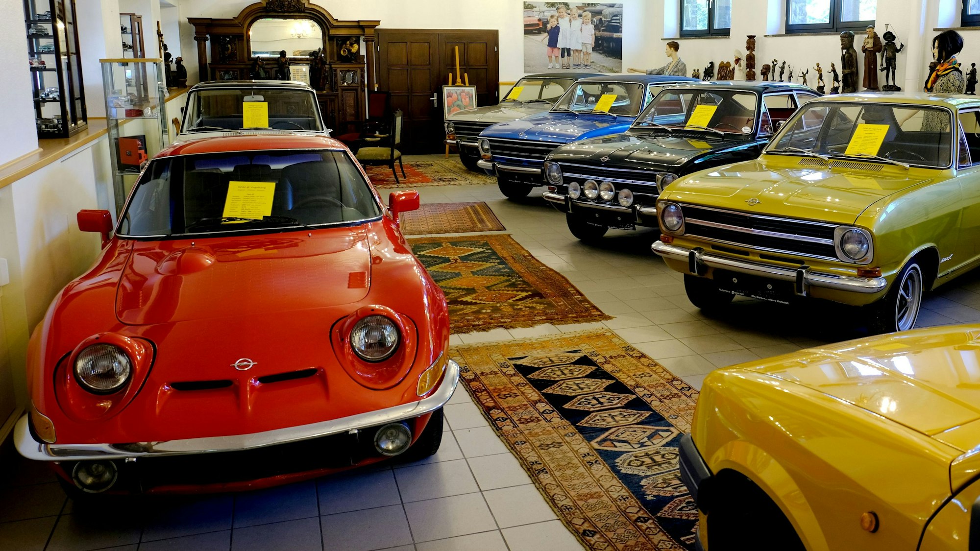 Blick in eine Ausstellungshalle des Opel-Museums in Vogelsang. Auf dem gekachelten Boden liegen Teppiche.