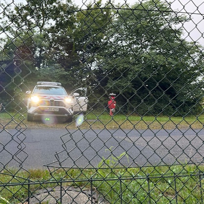 Ein Auto der Flughafensicherheit des Flughafen Köln-Bonn steht hinter dem Zaun des Flughafens. Die Polizei geht davon aus, dass Aktivisten der Klima-Initiative Letzte Generation durch das sichtbare Loch im Zaun auf das Gelände des Flughafens gelangt sind.