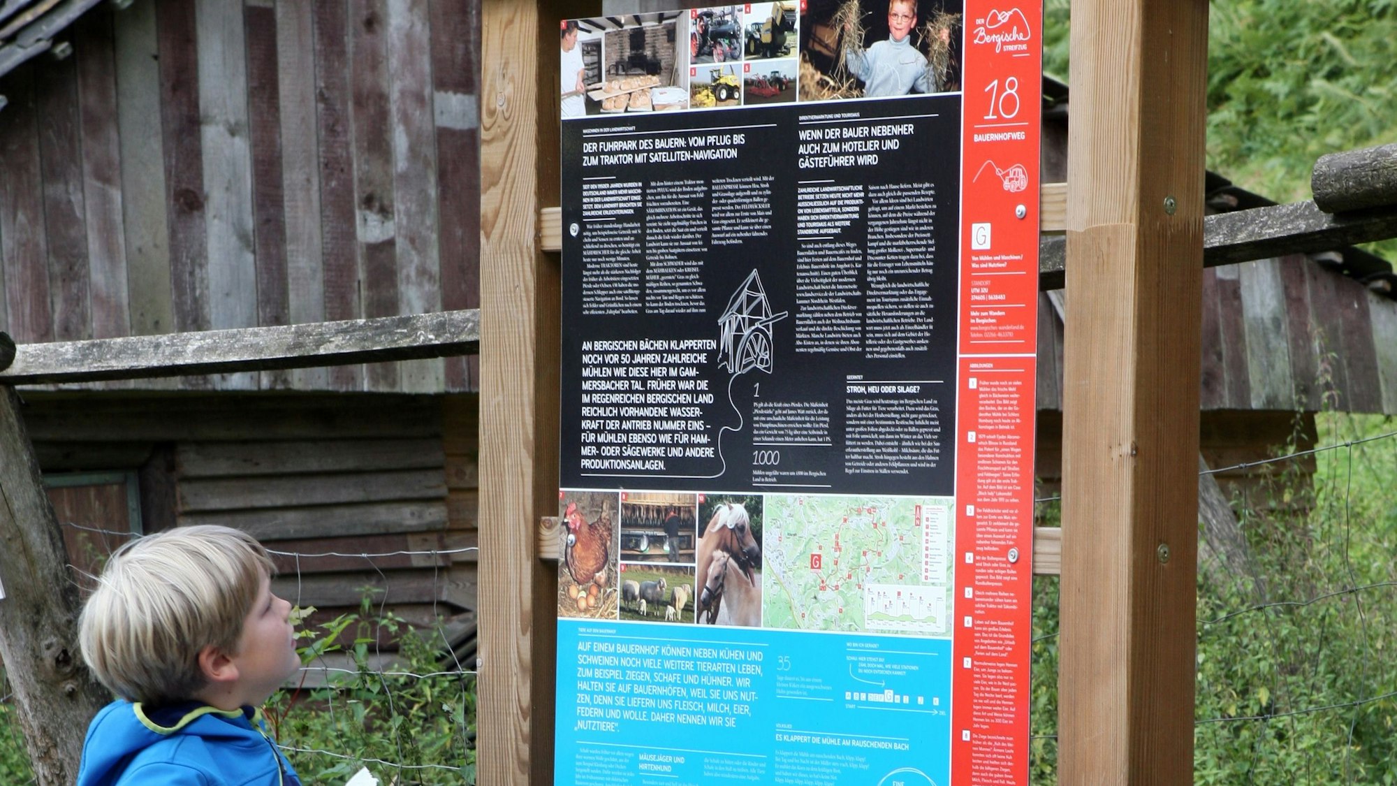 Ein Kind schaut auf eine Infotafel am Bauernhofweg bei Lohmar.