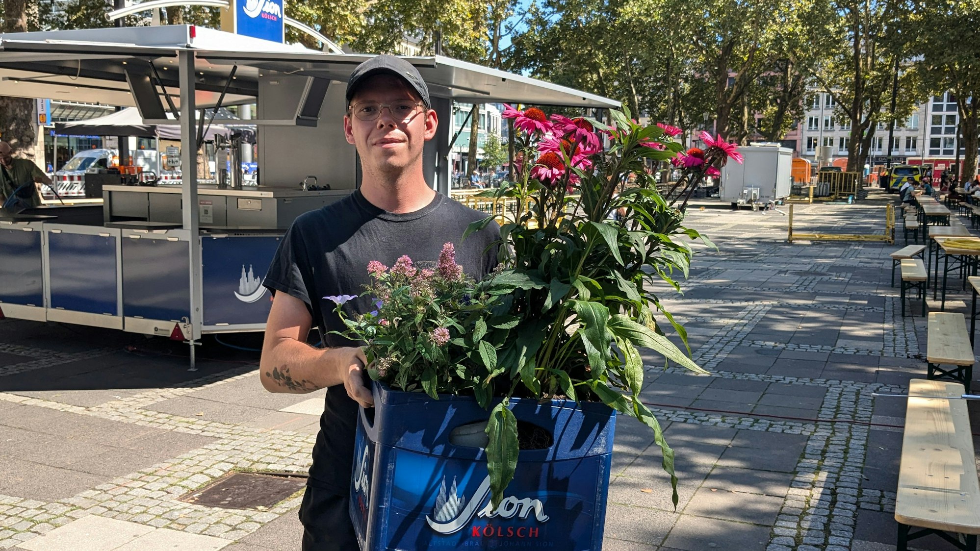 Maurice Lawnik hält eine Blume in der Hand beim Street Food & Music Festival-Aufbau in Köln