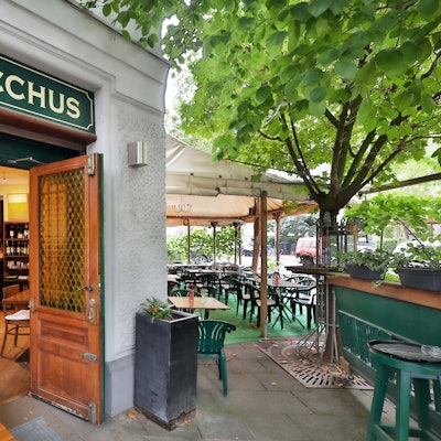 Die Weinstube Bacchus liegt am Rathenauplatz in Köln. Zu sehen ist ein warm beleuchtes Fenster.