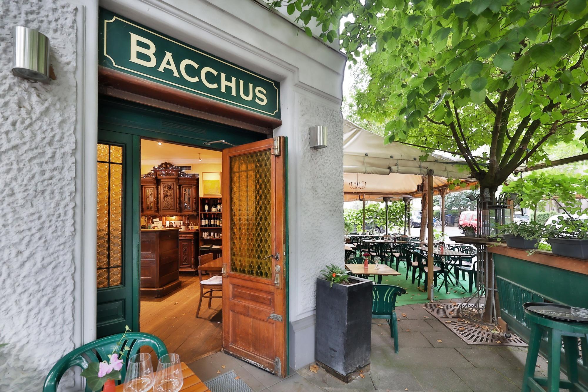 Die Weinstube Bacchus liegt am Rathenauplatz in Köln. Zu sehen ist ein warm beleuchtes Fenster.