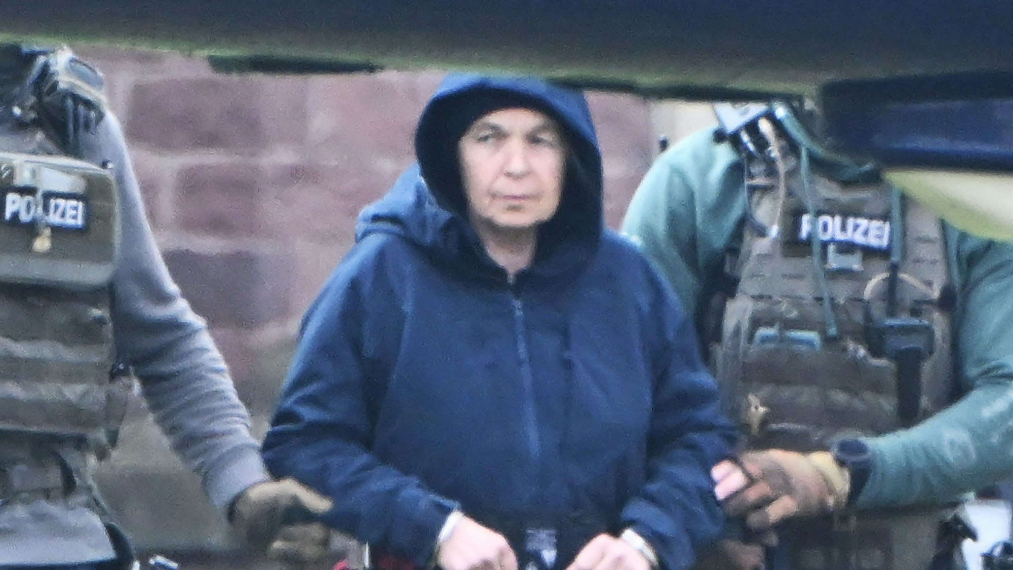 Im Innenhof eines Behördenzentrums wird die frühere RAF-Terroristin Daniela Klette zu einem Hubschrauber geführt.