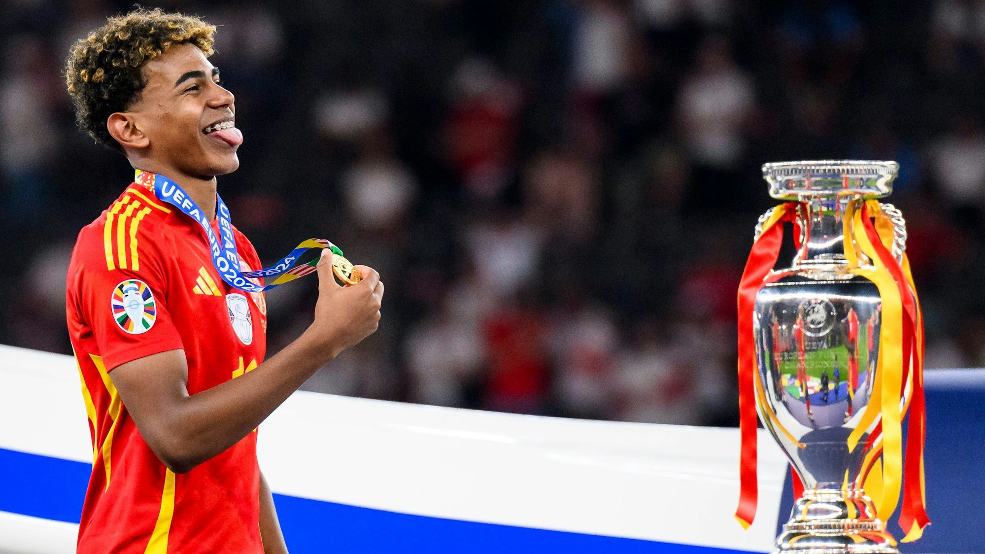 Spaniens Lamine Yamal jubelt mit seiner Medaille neben dem EM-Pokal bei der Siegerehrung.