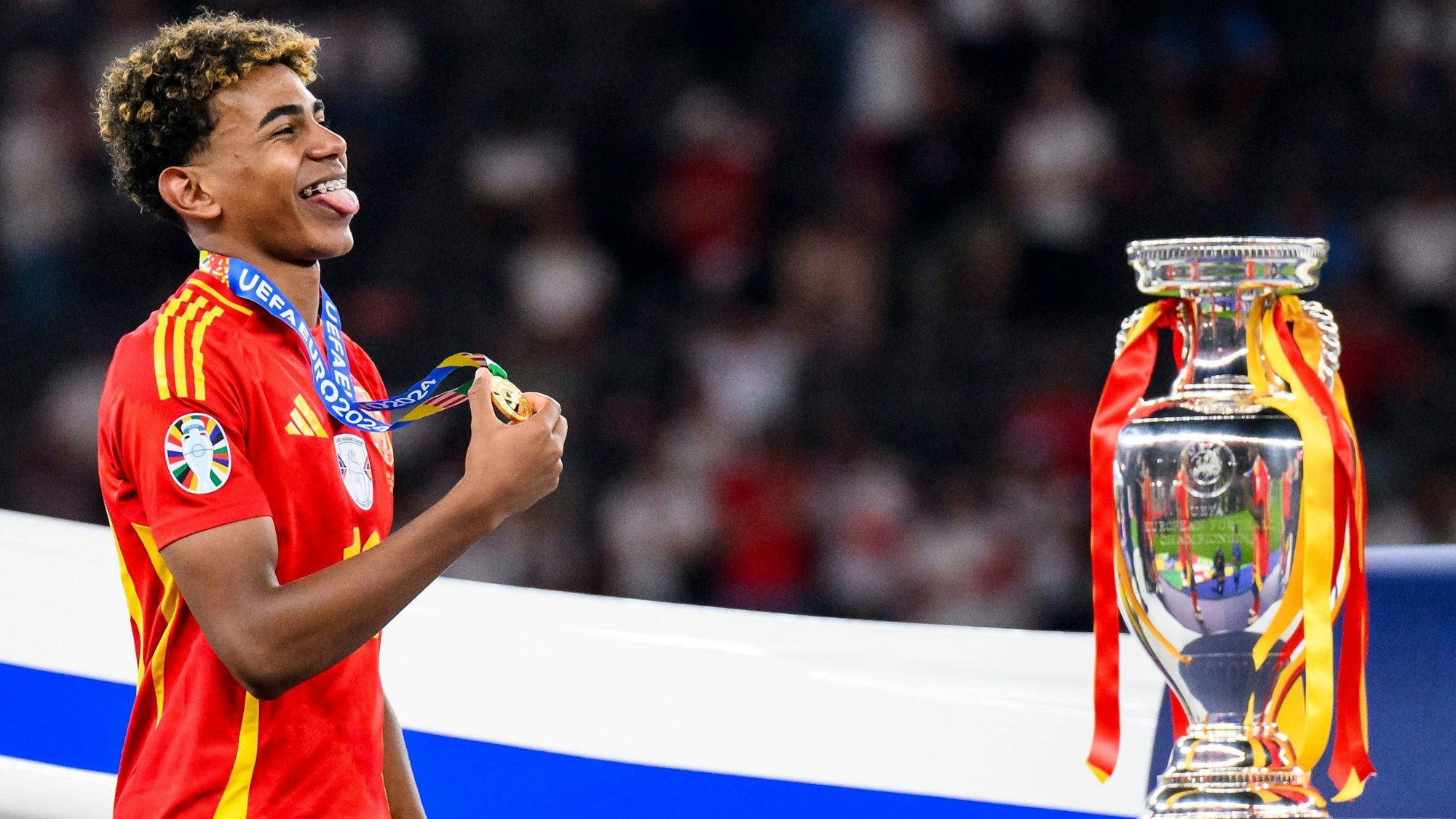 Spaniens Lamine Yamal jubelt mit seiner Medaille neben dem EM-Pokal bei der Siegerehrung.