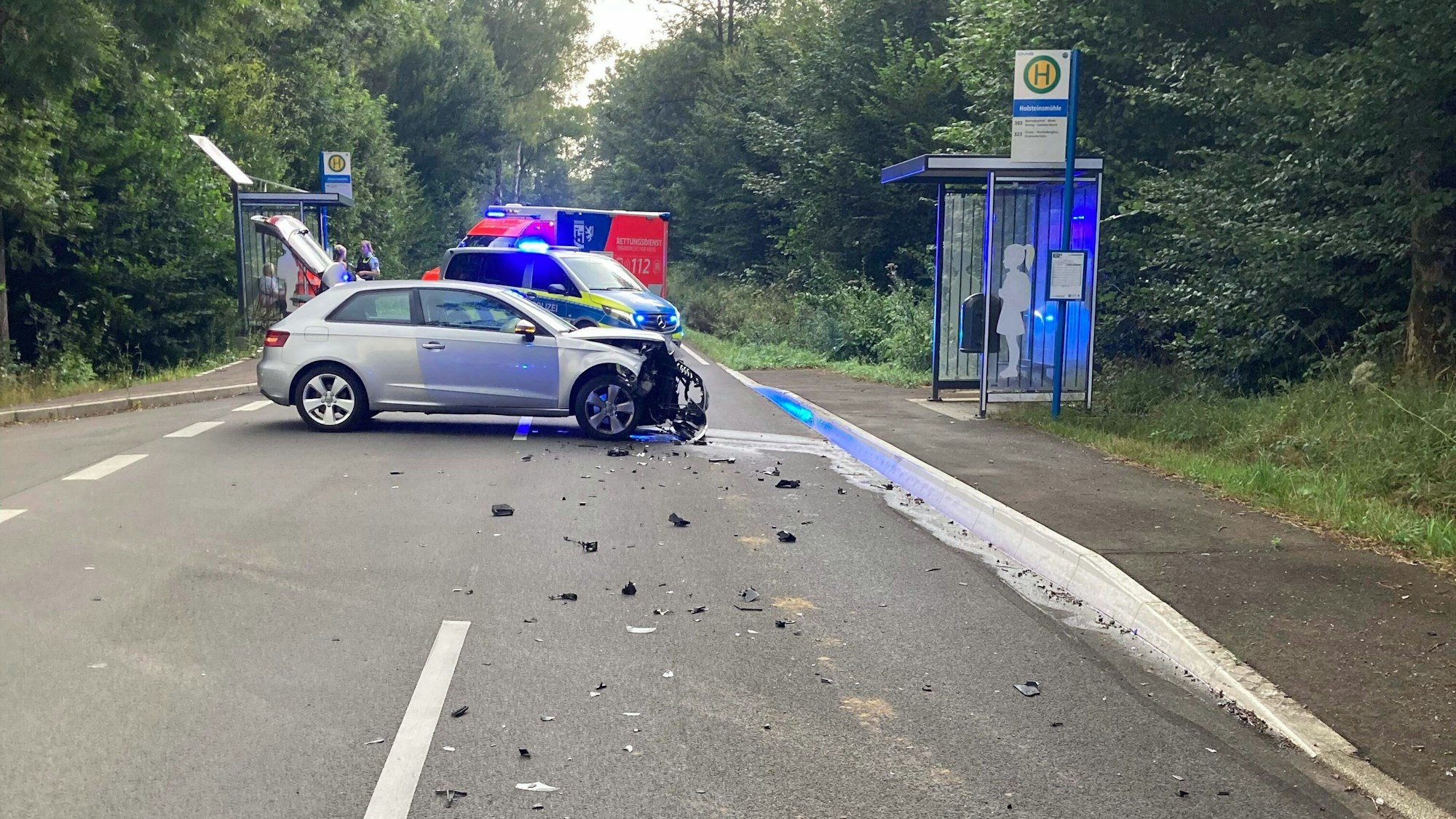 Unfallbild nach einem Zusammenstoß zweier Pkw auf einer Straße. Ein Rettungswagen ist im Hintergrund zu sehen.