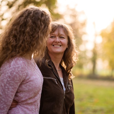 Zwei Frauen schauen sich beim Spazierengehen lächelnd an