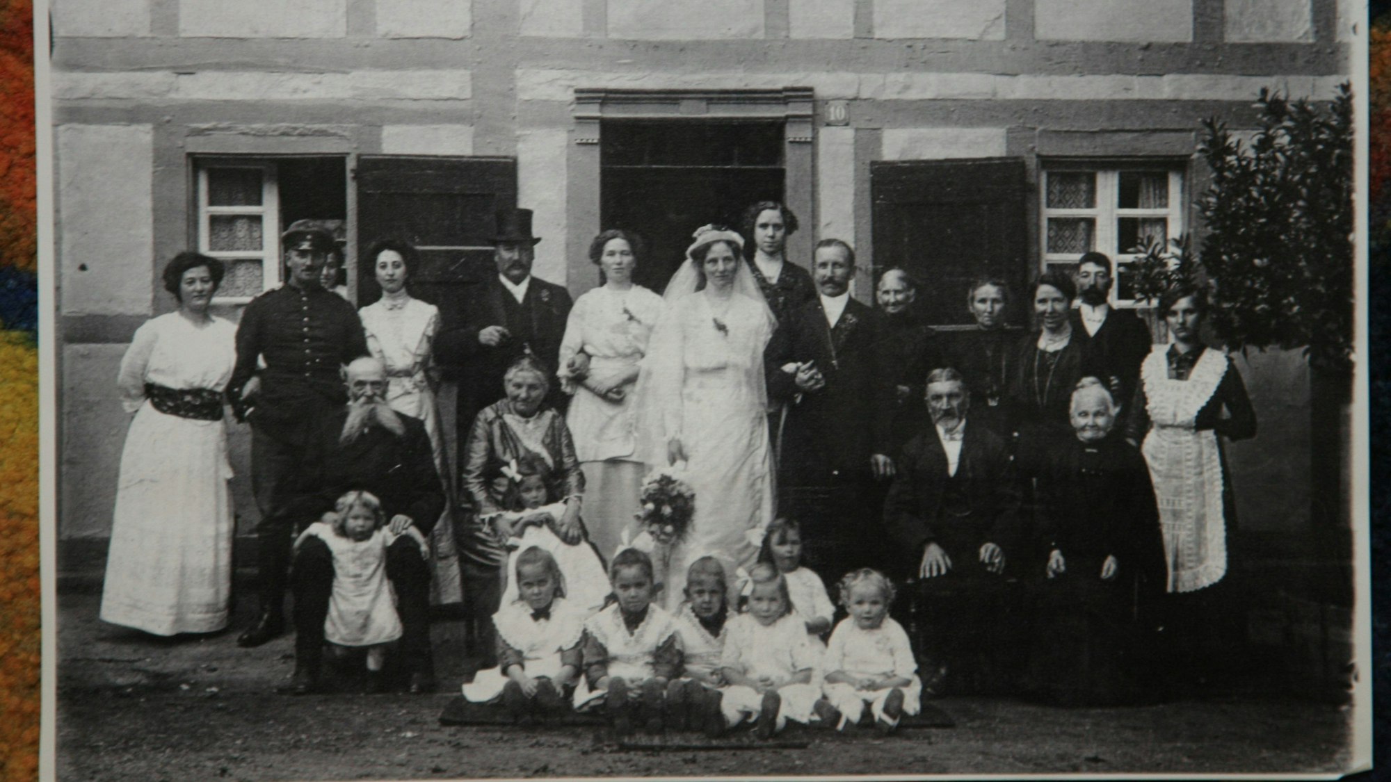 In drei Reihen aufgereiht stehen die Familienmitglieder anlässlich eines Hochzeitfotos.