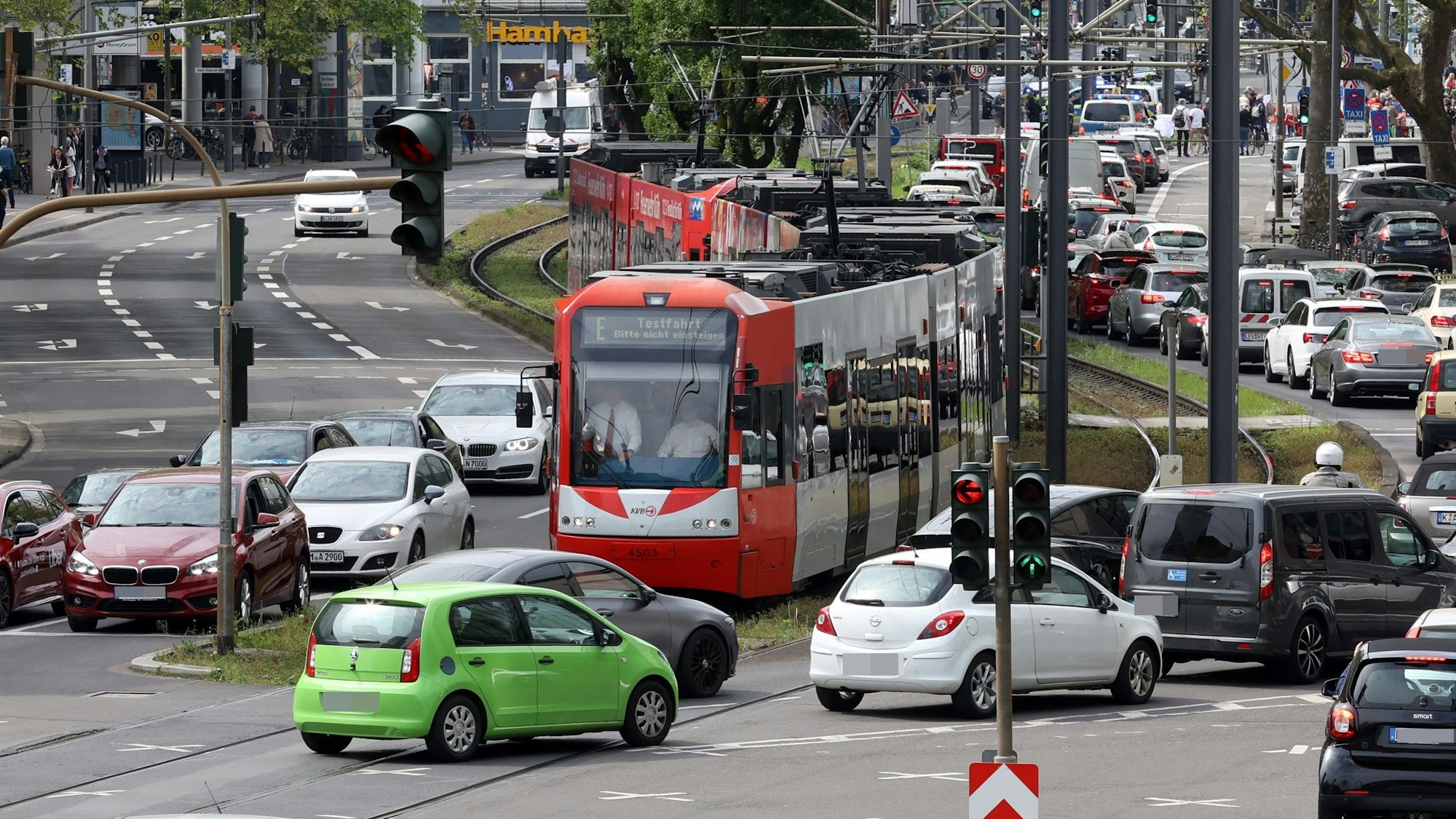 Eine Straßenbahn steht am Eingang zum Neumarkt. Autos kreuzen ihren Weg.