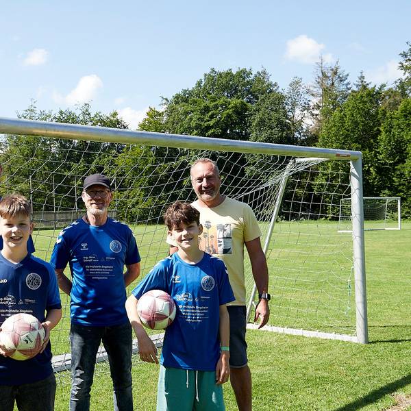 Drei Männer und zwei Jungen stehen vor einem Fußballtor.