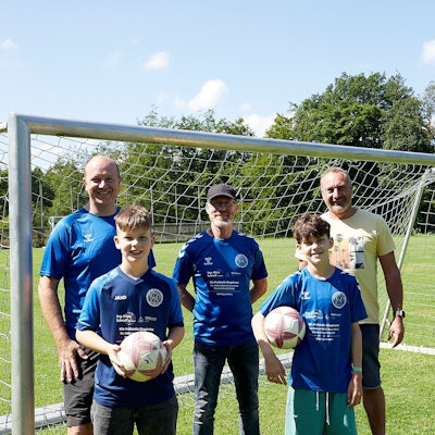Drei Männer und zwei Jungen stehen vor einem Fußballtor.