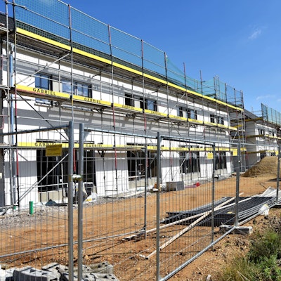 Ein Mehrfamilienhaus mit Gerüst im Rohbau.
