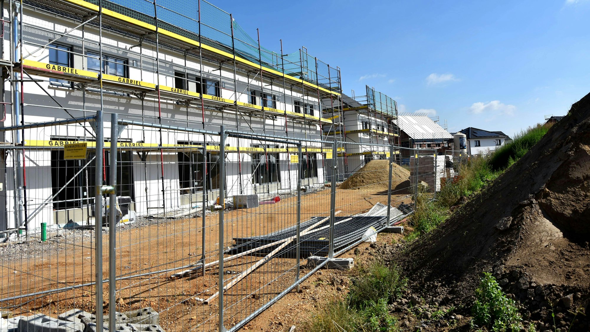 Ein Mehrfamilienhaus mit Gerüst im Rohbau.