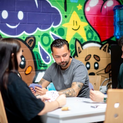 Erwachsene Spielen mit Kindern Karten an einem Tisch.