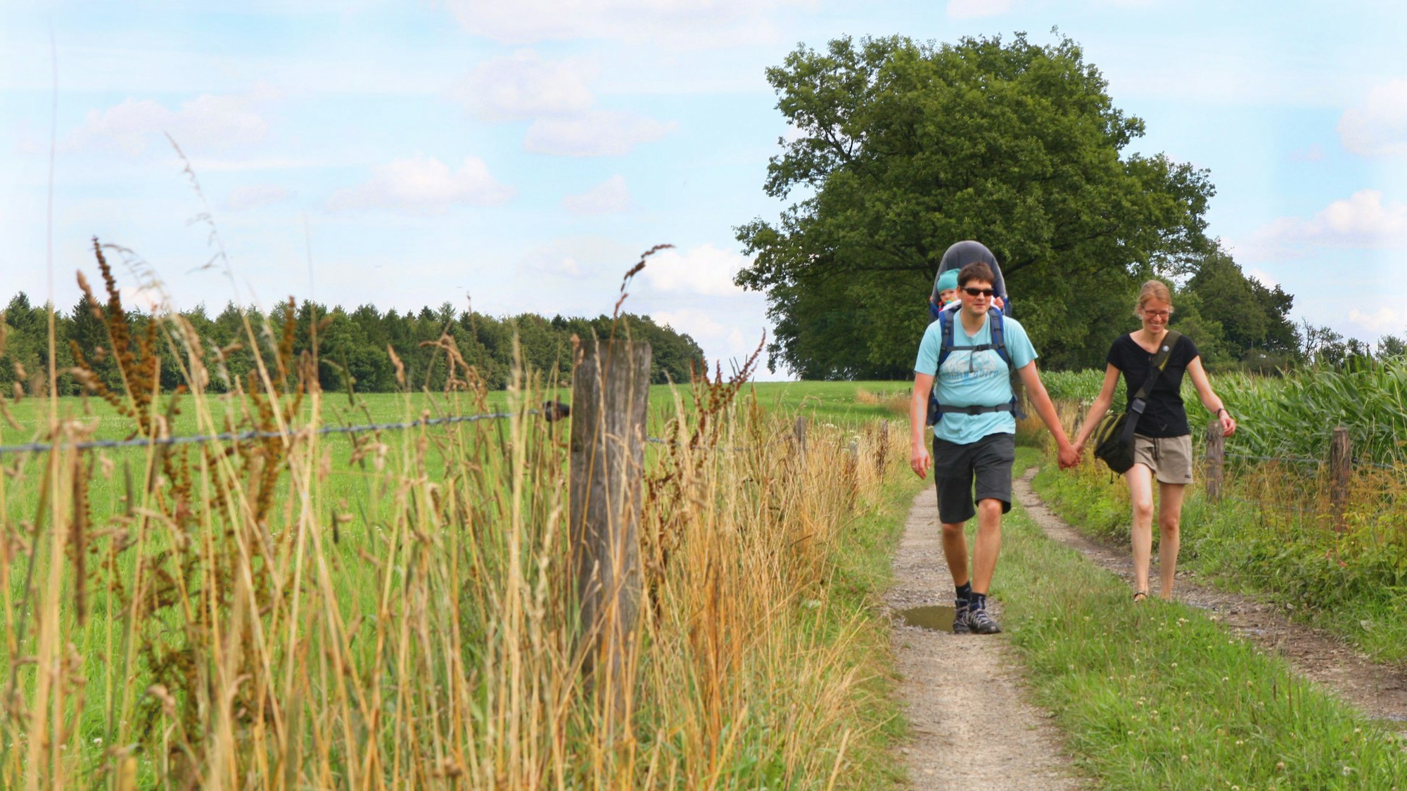 Ein Paar wandert auf mit einer Kindertrage im Bergischen Wanderland.