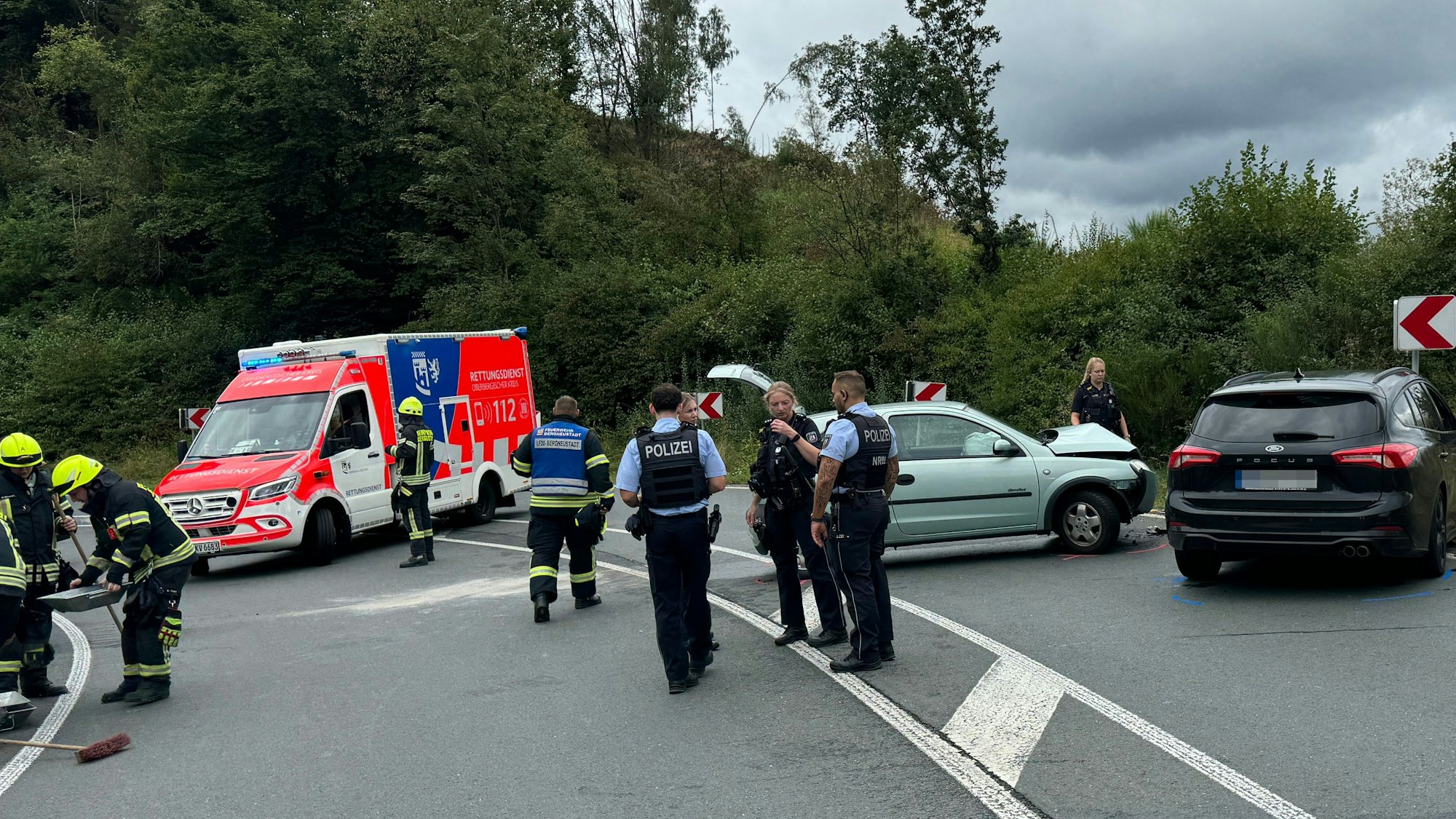 Das Foto zeigt eine Unfallstelle mit zwei beschädigten Autos, sowie Einsatzkräften von Polizei, Rettungsdienst und Feuerwehr.