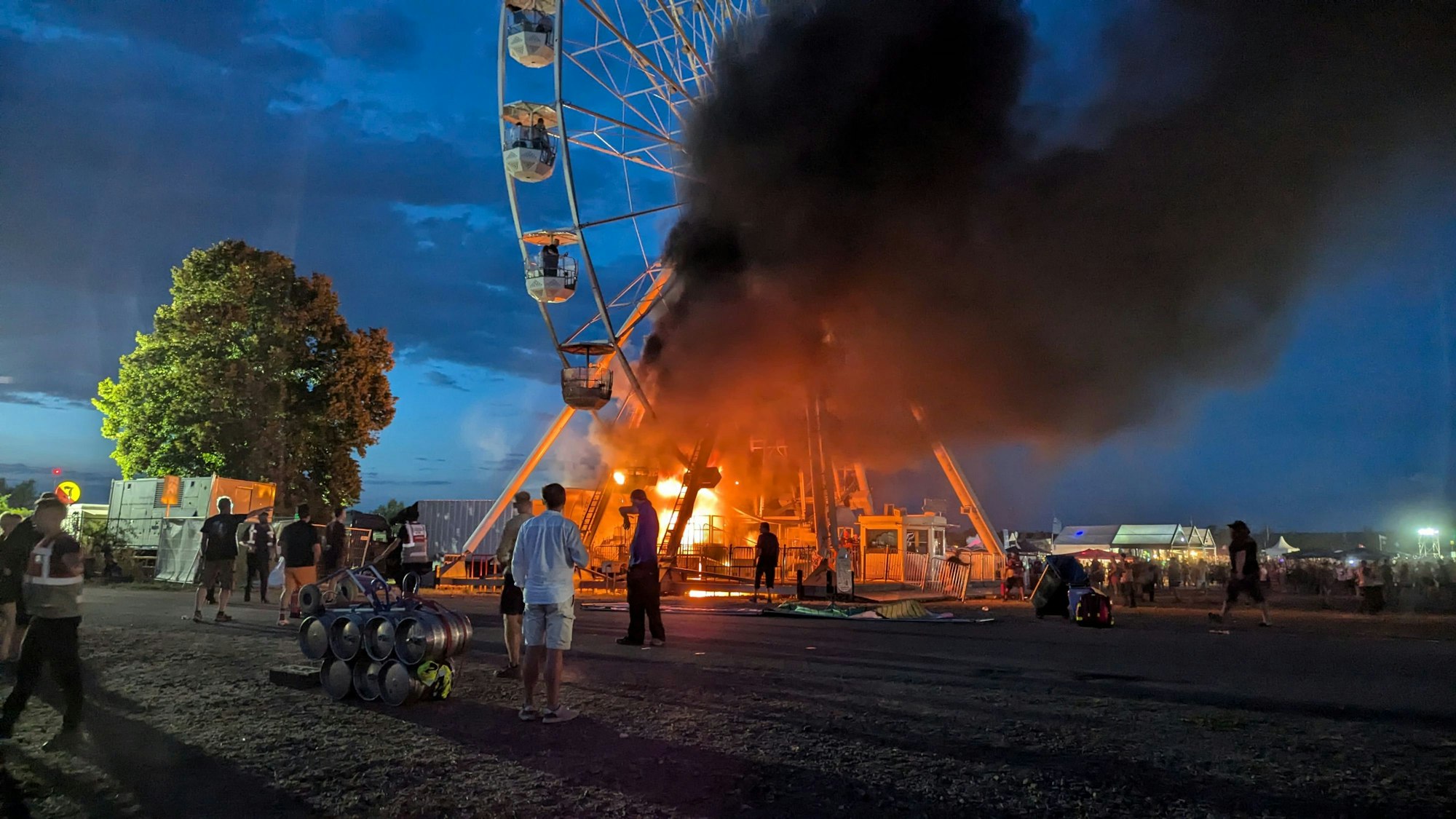 Besucher des Highfield-Festivals blicken auf ein Riesenrad, an dem Flammen zu sehen sind.