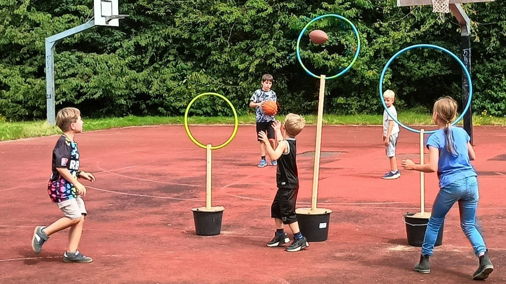 Kinder werfen Bälle durch Ringe.