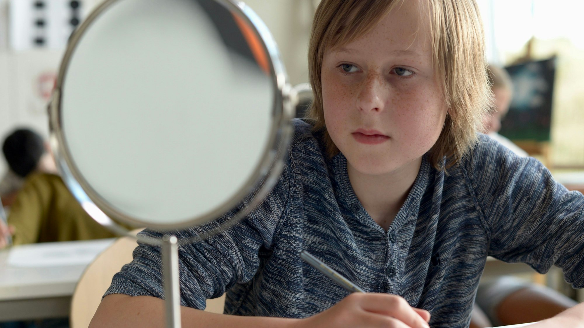 Ein Schüler schaut in einen Spiegel.