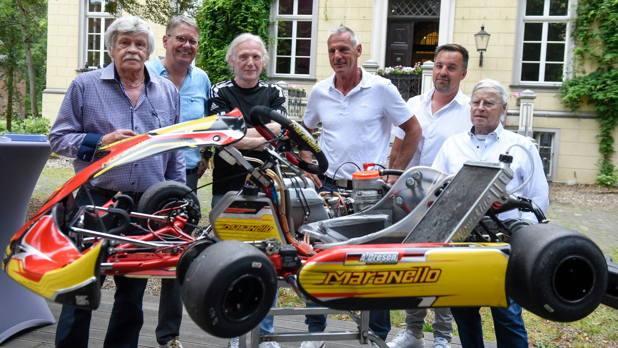 Mehrere Männer stehen hinter einem Kart.