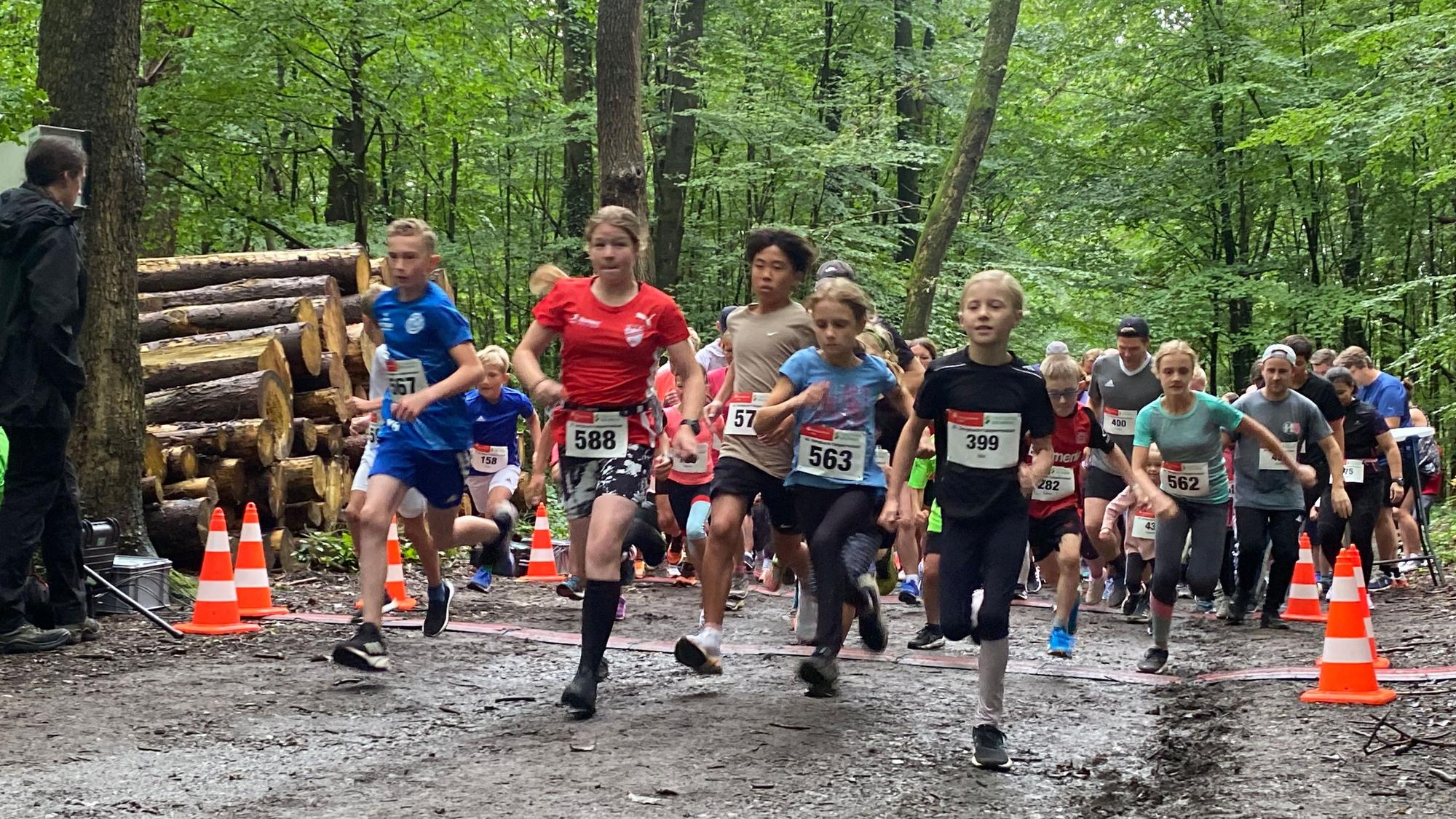 Kinder und Jugendlichen rennen durch einen Wald.