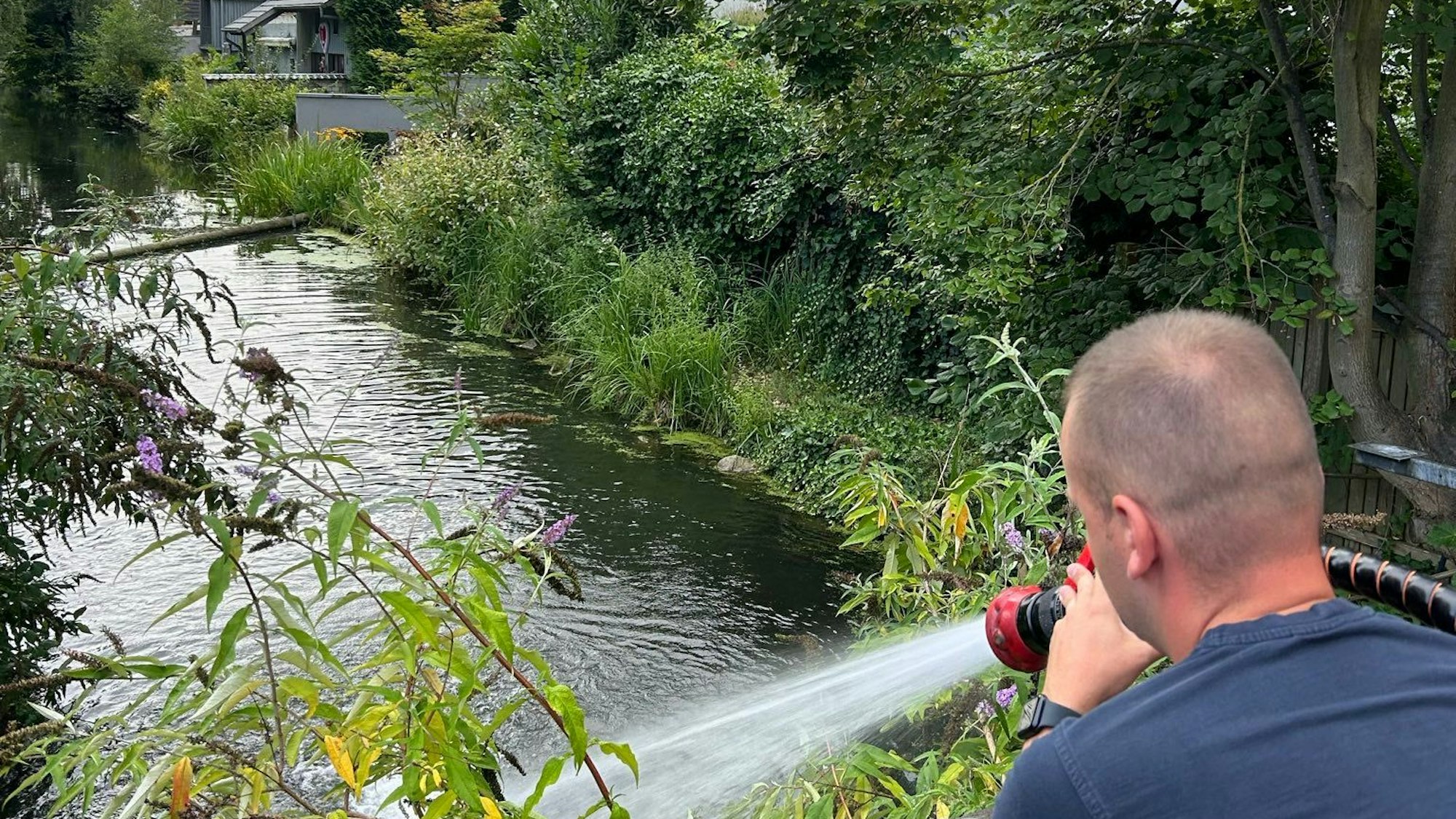 Ein Feuerwehrmann führt einem Gewässer Frischwasser zu.