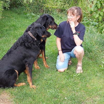Carina Niesen kniet bei ihren beiden schwarzen Beauceron-Hütehunden Juna (hinten) und Mora.