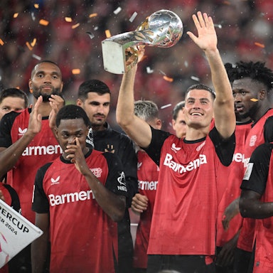 Leverkusens Patrik Schick hält in mitten des jubelnden Teams den Supercup.