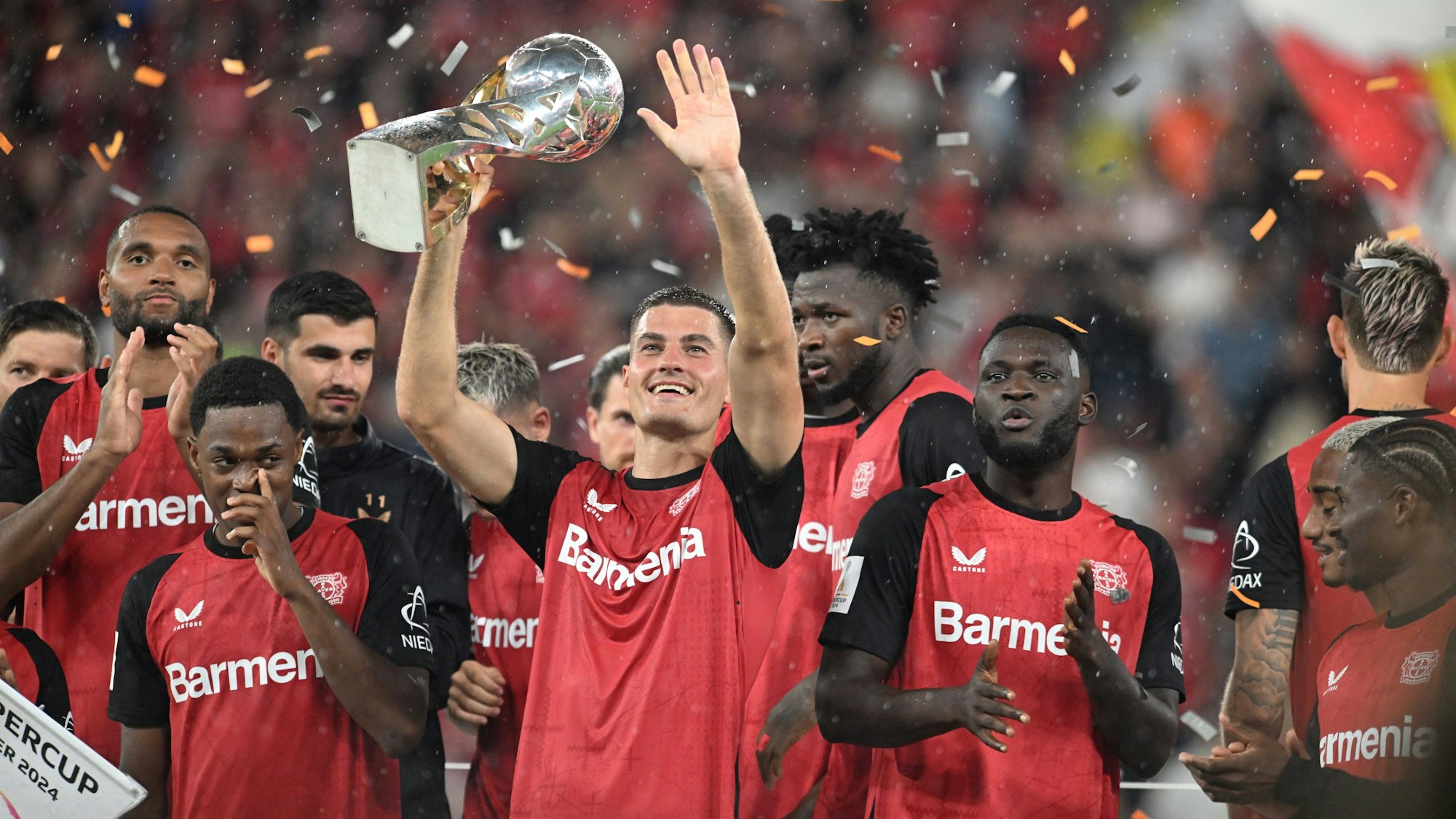 Leverkusens Patrik Schick hält in mitten des jubelnden Teams den Supercup.
