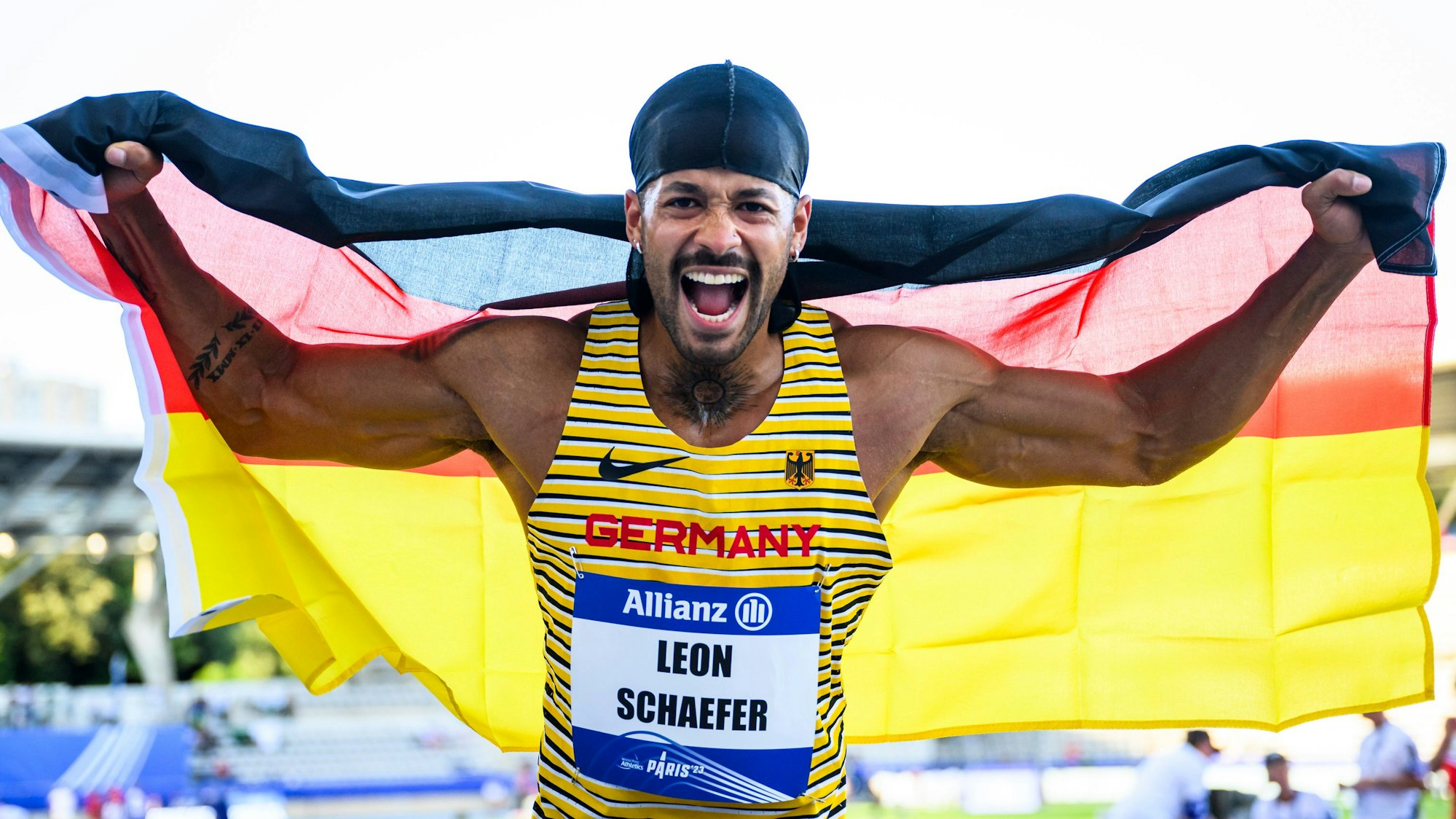Weitspringer Léon Schäfer aus Deutschland jubelt mit der deutschen Nationalflagge beim Weitsprung-Finale bei der Para-WM in Paris 2023.