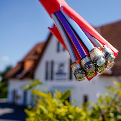 Ein Bündel mit Umhüllungen für Glasfaserkabel hängt vor einem Wohnhaus.