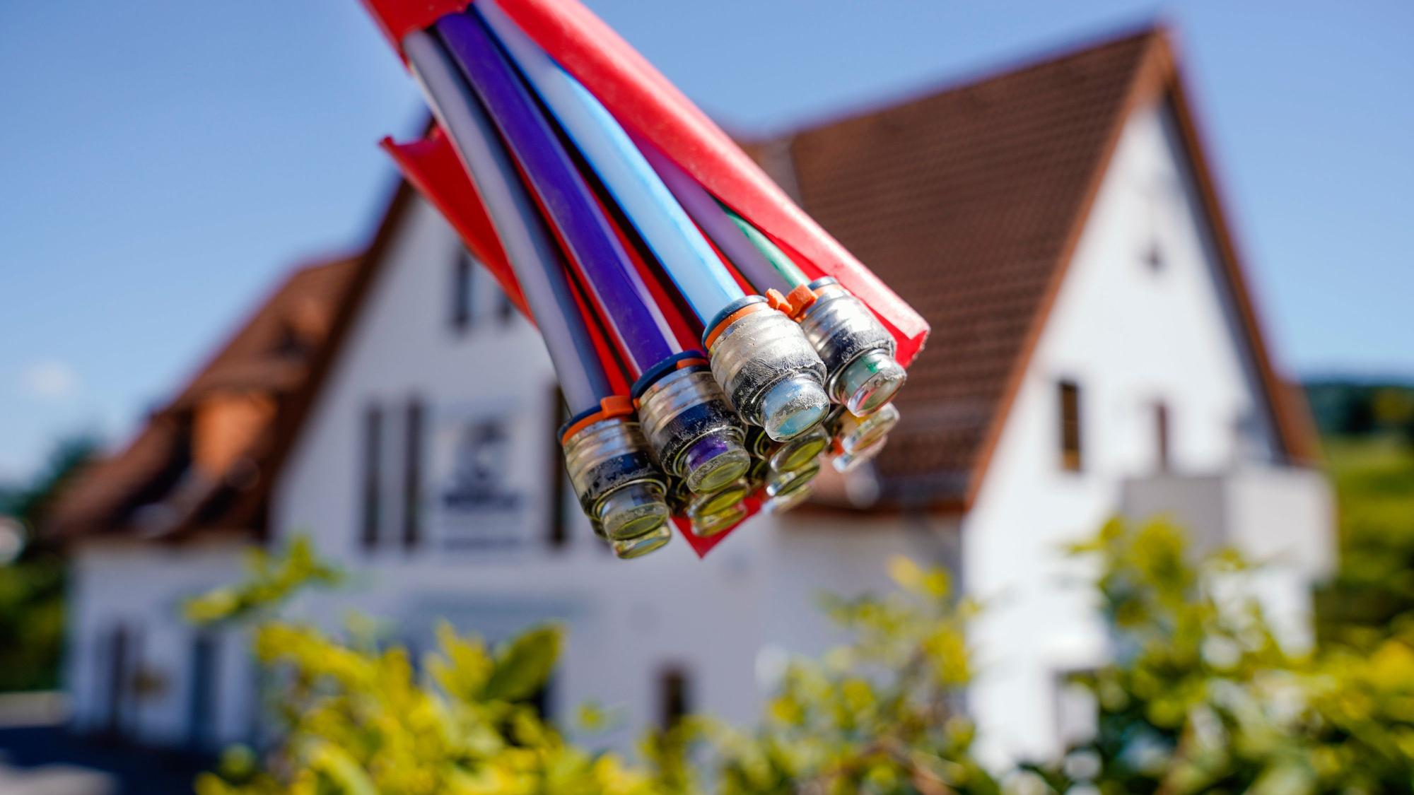 Ein Bündel mit Umhüllungen für Glasfaserkabel hängt vor einem Wohnhaus.