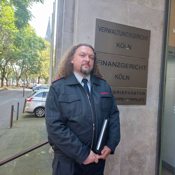 Foto eines Mannes, der vor dem Gebäude des Kölner Verwaltungsgerichtes steht.