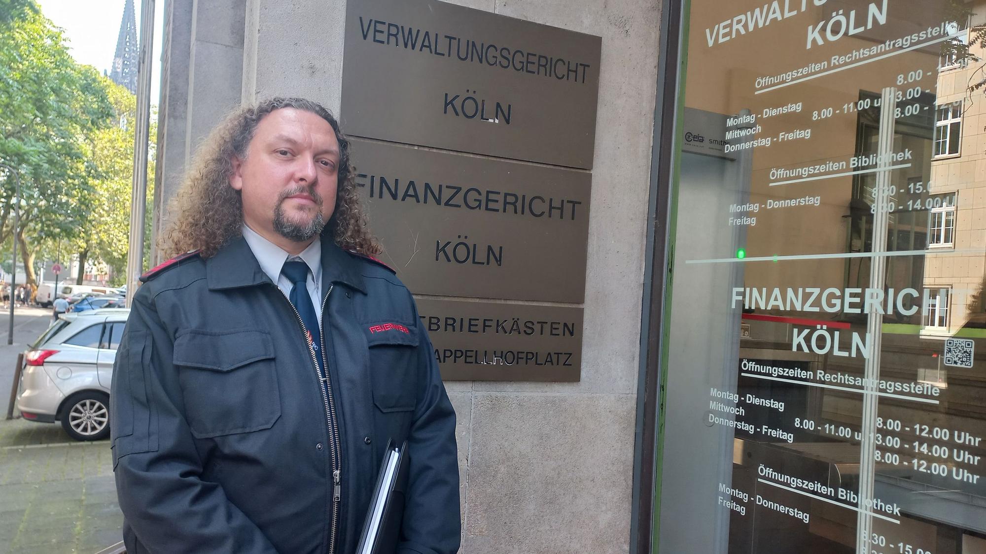 Foto eines Mannes, der vor dem Gebäude des Kölner Verwaltungsgerichtes steht.