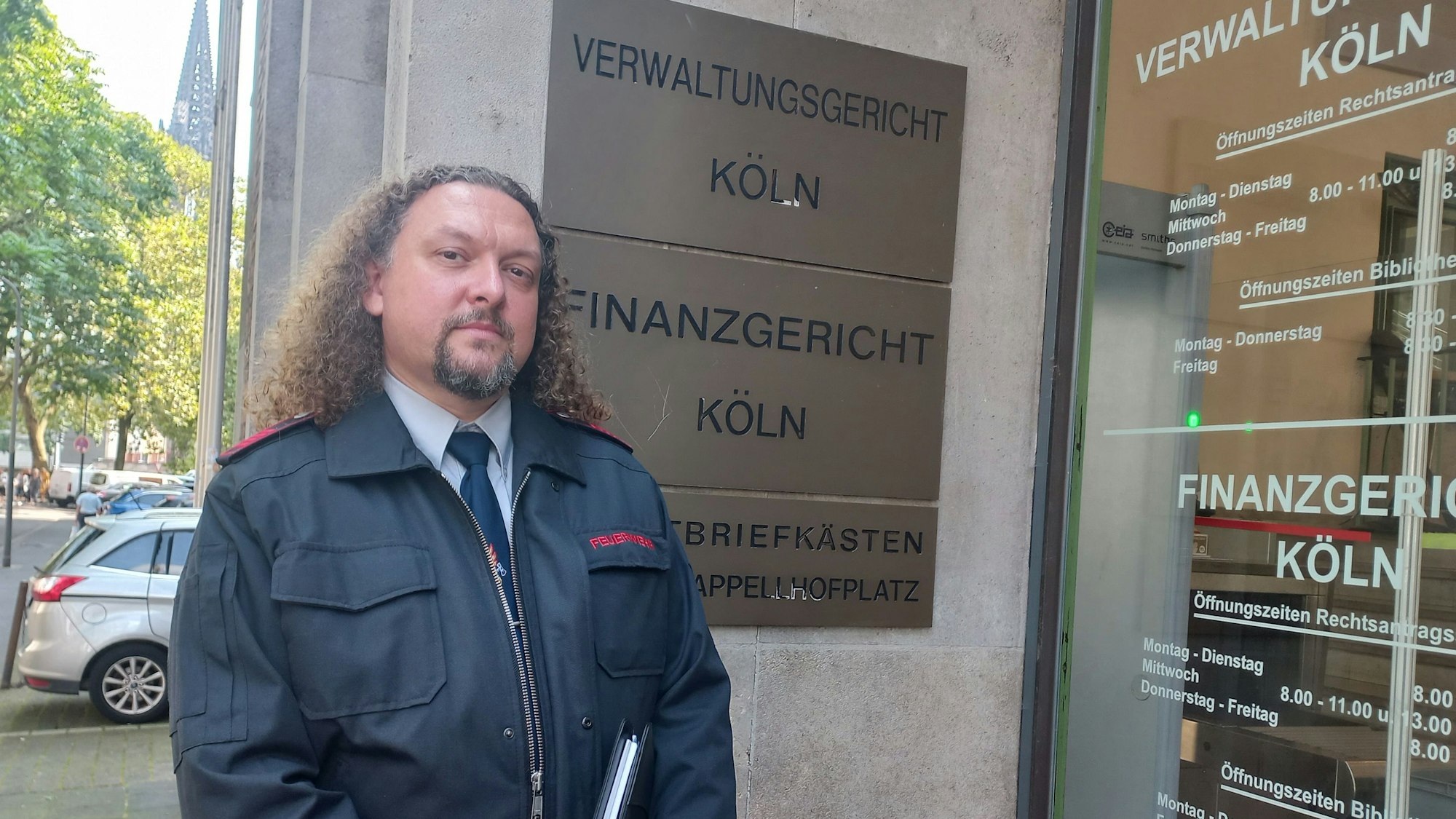Bild eines Feuerwehrmannes in Uniform vor dem Gebäude des Kölner Verwaltungsgerichtes am Appellhofplatz