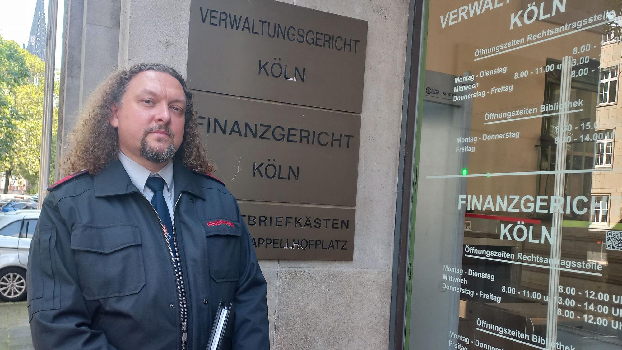 Zu sehen ist ein Feuerwehrmann vor dem Gebäude des Kölner Verwaltungsgerichts.