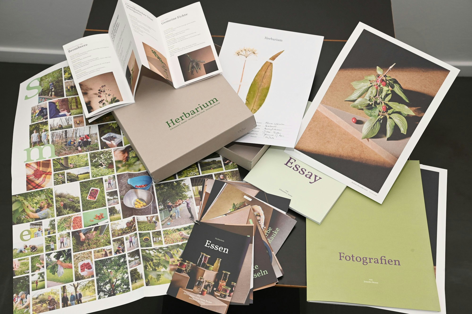 Hefte und Bilder mit Pflanzen liegen auf einem Tisch ausgebreitet.