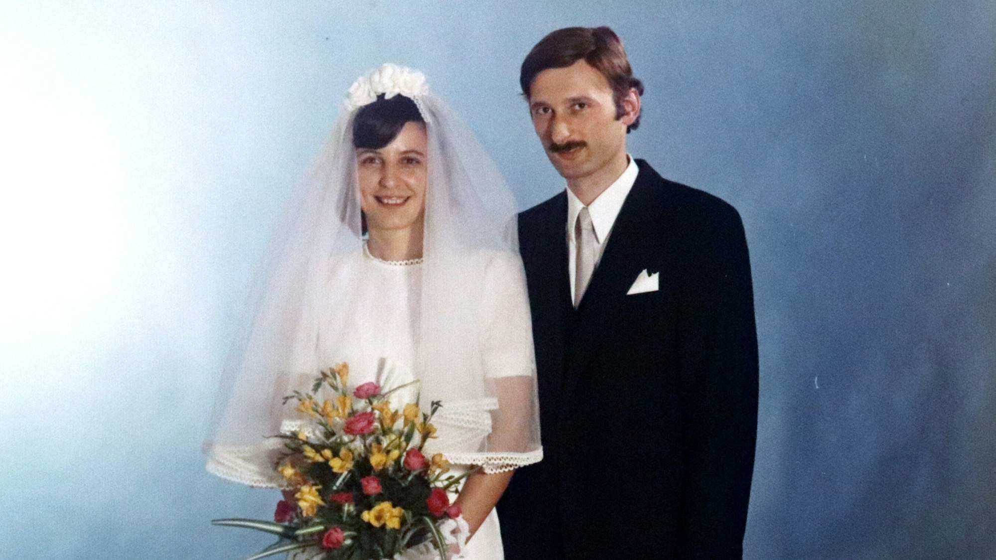 Zu sehen ist ein Ehepaar an seinem Hochzeitstag.