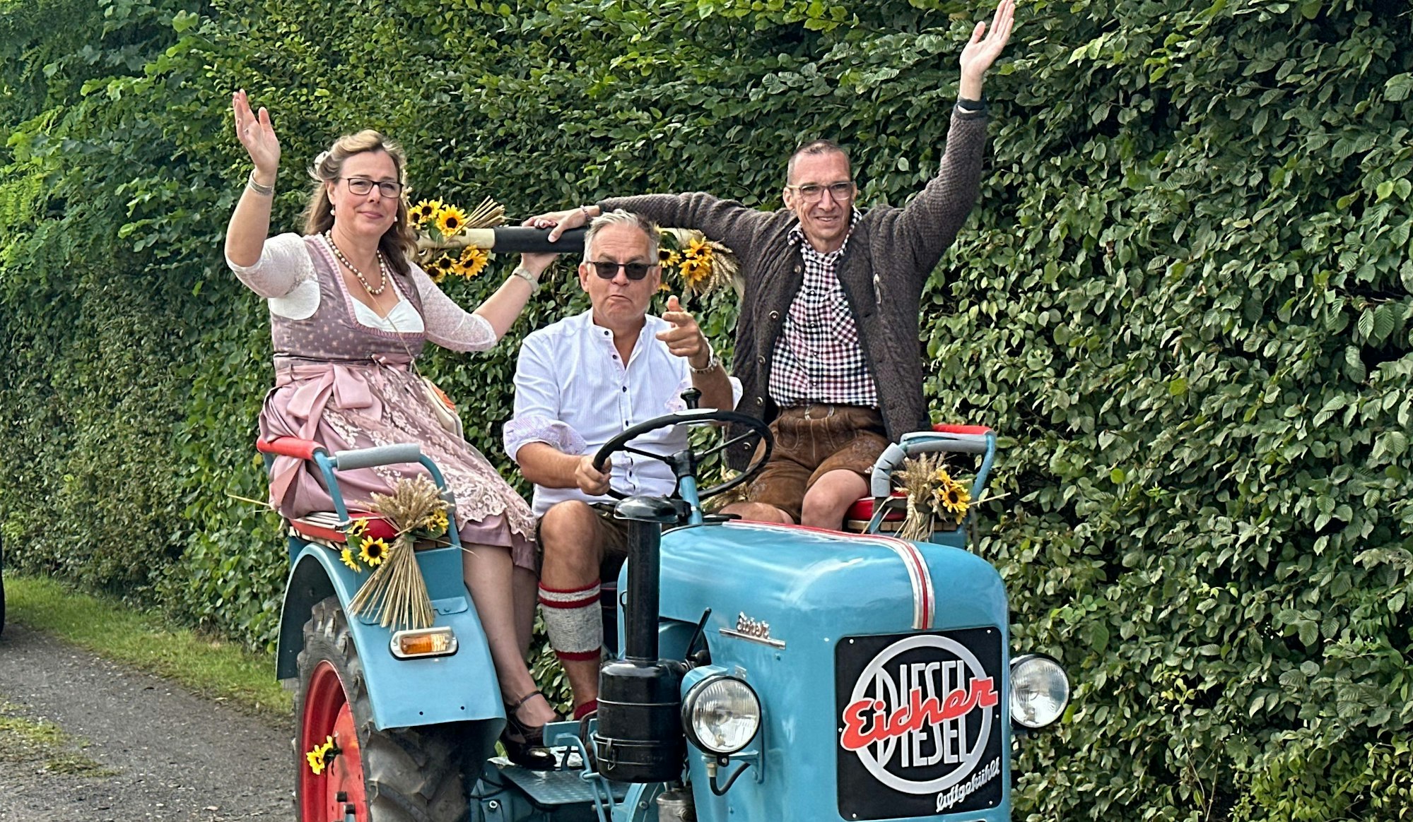 Auf einem Traktor der Marke Eicher Diesel sitzend fährt das Erntepaar Frauke und Thorsten Haas in Much-Markelsbach zum Festzelt.