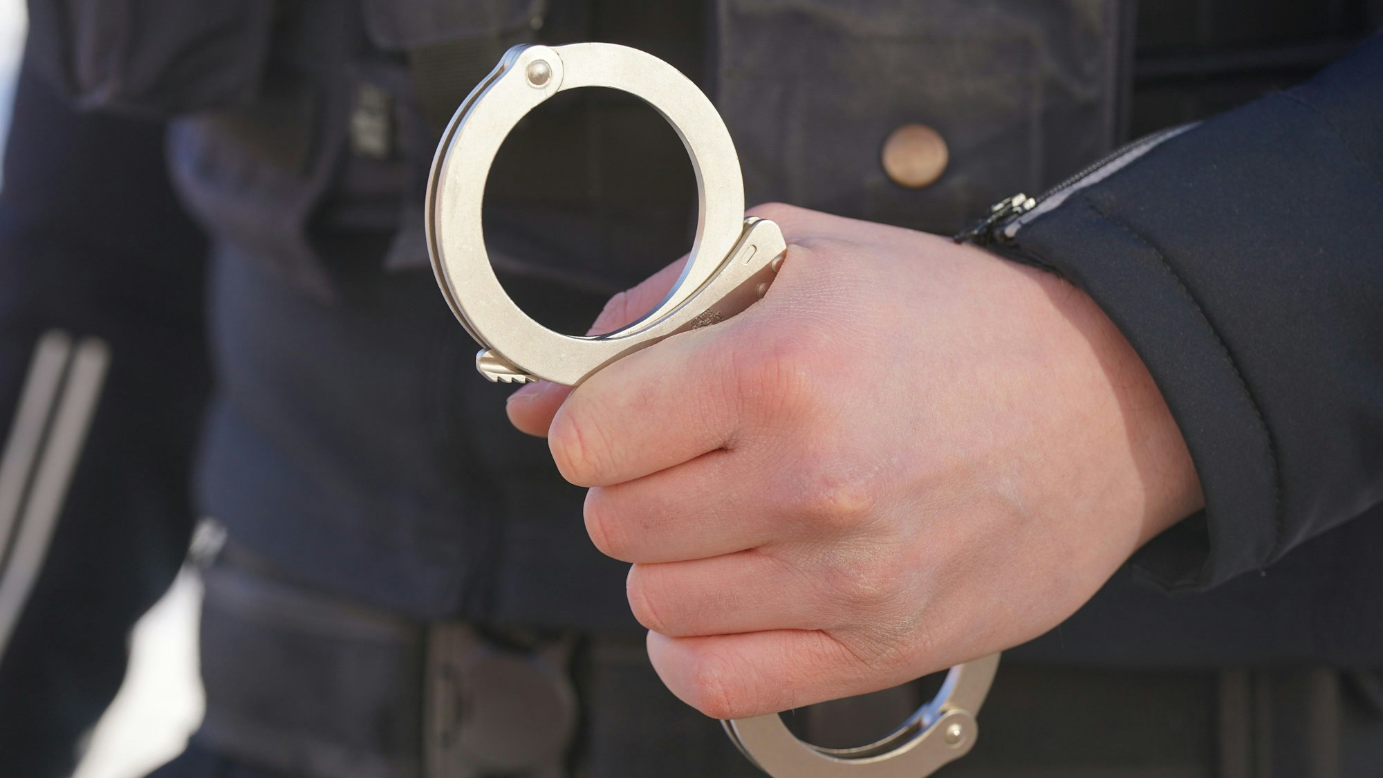 Ein Polizist hält Handschellen in der Hand.