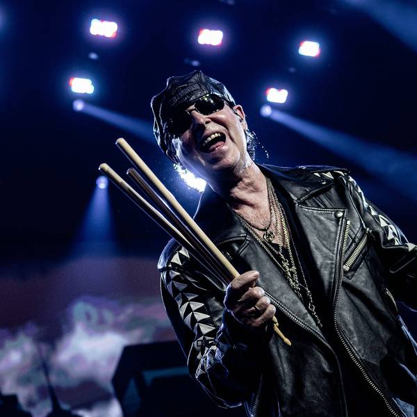Scorpions-Sänger trägt Sonnenbrille, Leder-Käppi und -jacke auf der Bühne der Wembley-Arena in London. In der rechten Hand hält er mehrere Drum-Sticks.