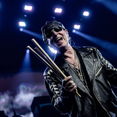 Scorpions-Sänger trägt Sonnenbrille, Leder-Käppi und -jacke auf der Bühne der Wembley-Arena in London. In der rechten Hand hält er mehrere Drum-Sticks.