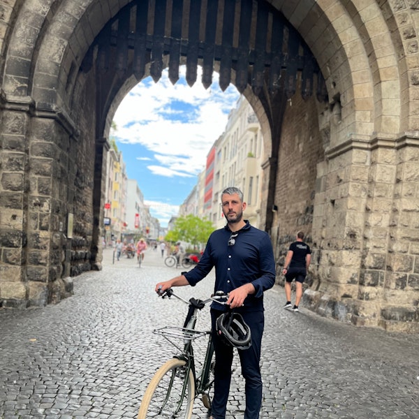 German Moyzhes steht mit einem Fahrrad vor der Severinstorburg.