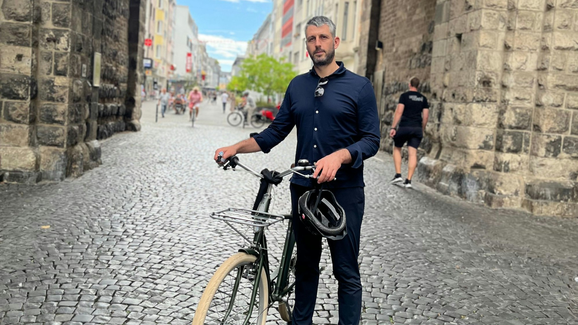 German Moyzhes steht mit einem Fahrrad vor der Severinstorburg.