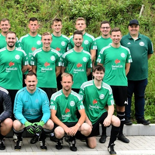 Das Mannschaftsfoto zeigt die Mitglieder des SV Schöneseiffen auf hartem, gekachelten Untergrund vor einer Grünfläche.