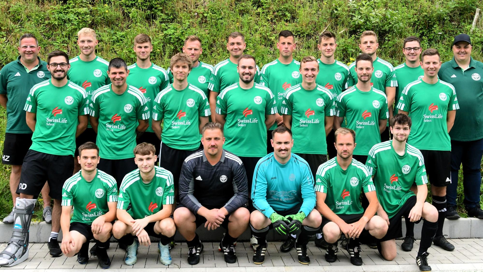 Das Mannschaftsfoto zeigt die Mitglieder des SV Schöneseiffen auf hartem, gekachelten Untergrund vor einer Grünfläche.