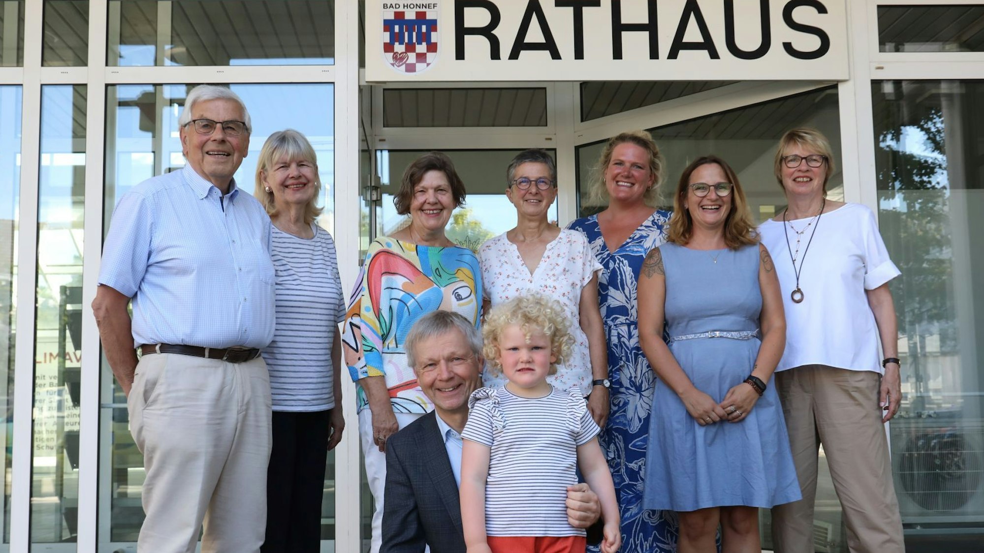 Eine Gruppe Erwachsener mit einem kleinen Mädchen vor dem Eingang zum Bad Honnefer Rathaus.