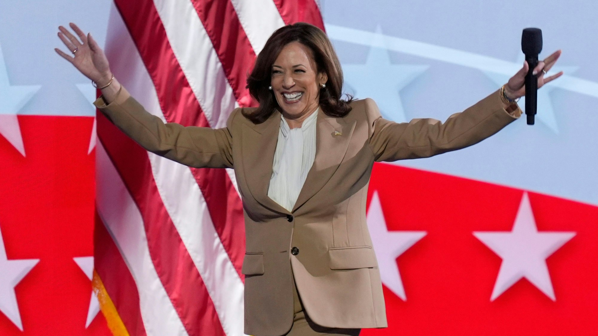 Die demokratische US-Präsidentschaftskandidatin und US-Vizepräsidentin Kamala Harris hebt die Arme, als sie während der Democratic National Convention in Chicago die Bühne betritt.