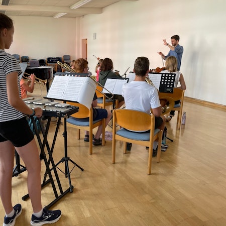 Nico Köhr zeigt den jungen Musikerinnen und Musikern, wie man dirigiert.