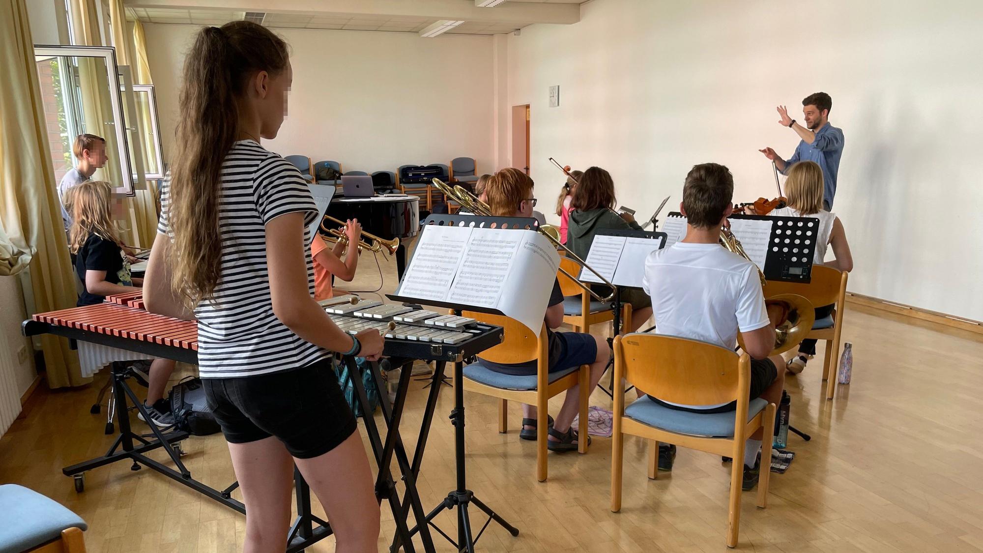 Nico Köhr zeigt den jungen Musikerinnen und Musikern, wie man dirigiert.